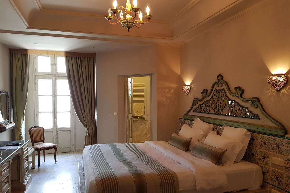 Una habitación de hotel con una cama grande, un escritorio, una silla y un candelabro.