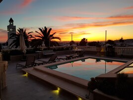 Una piscina al aire libre, sombrillas, sillones reclinables de piscina