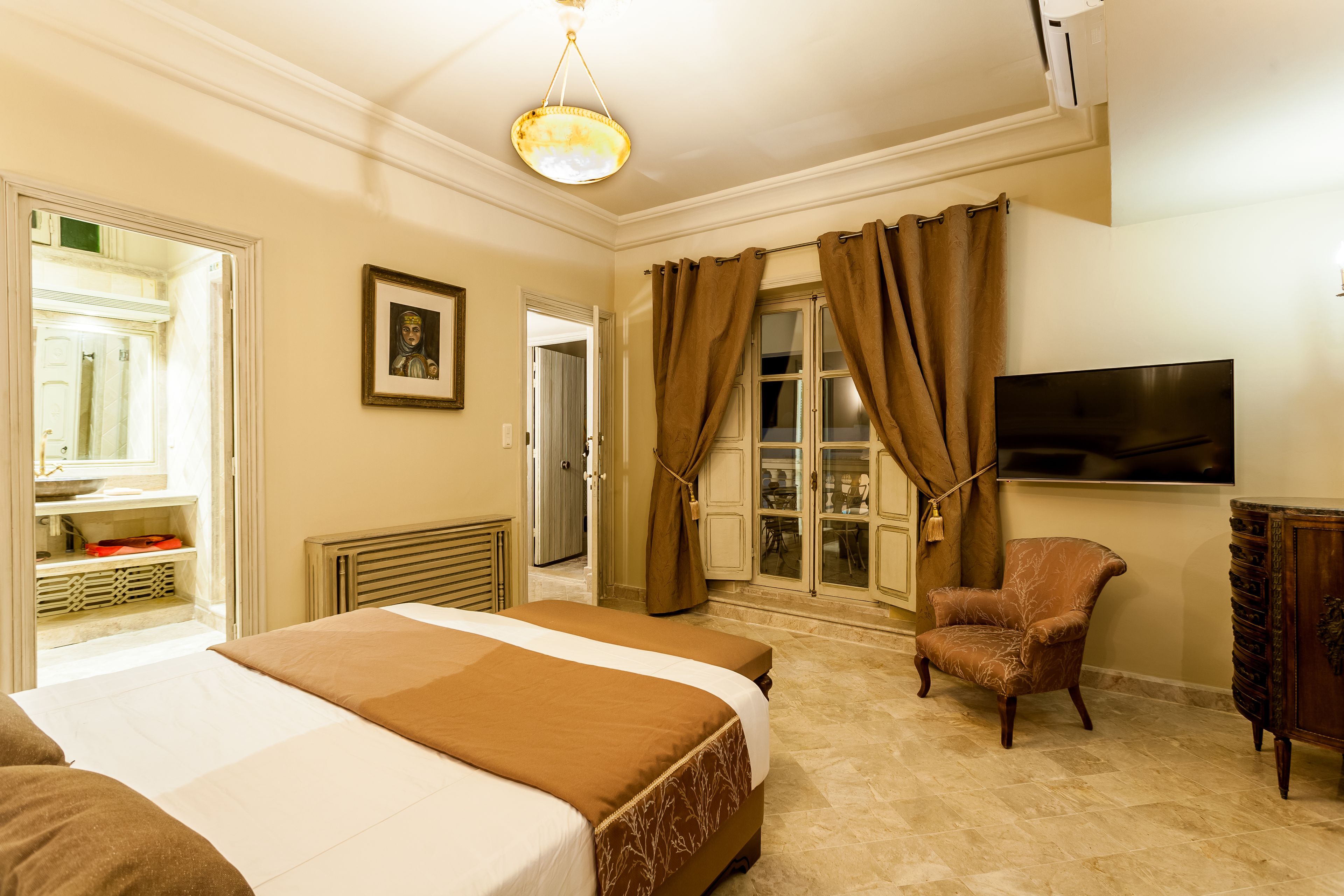 Een hotelkamer met een groot bed, een stoel, een televisie en een raam met gordijnen.