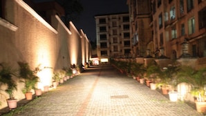 A nighttime view of a paved pathway flanked by buildings with potted plants. - Tim Grand Hotel (Mumbai)