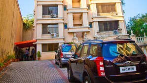 A multi-story building with a tiled roof, a visible balcony on the second floor, and a parked car in front. - Tim Grand Hotel (Mumbai)