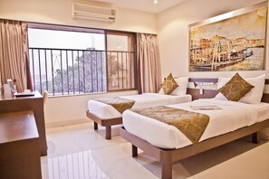 A hotel room with two beds, a desk, and a large window with curtains. - Tim Grand Hotel (Mumbai)