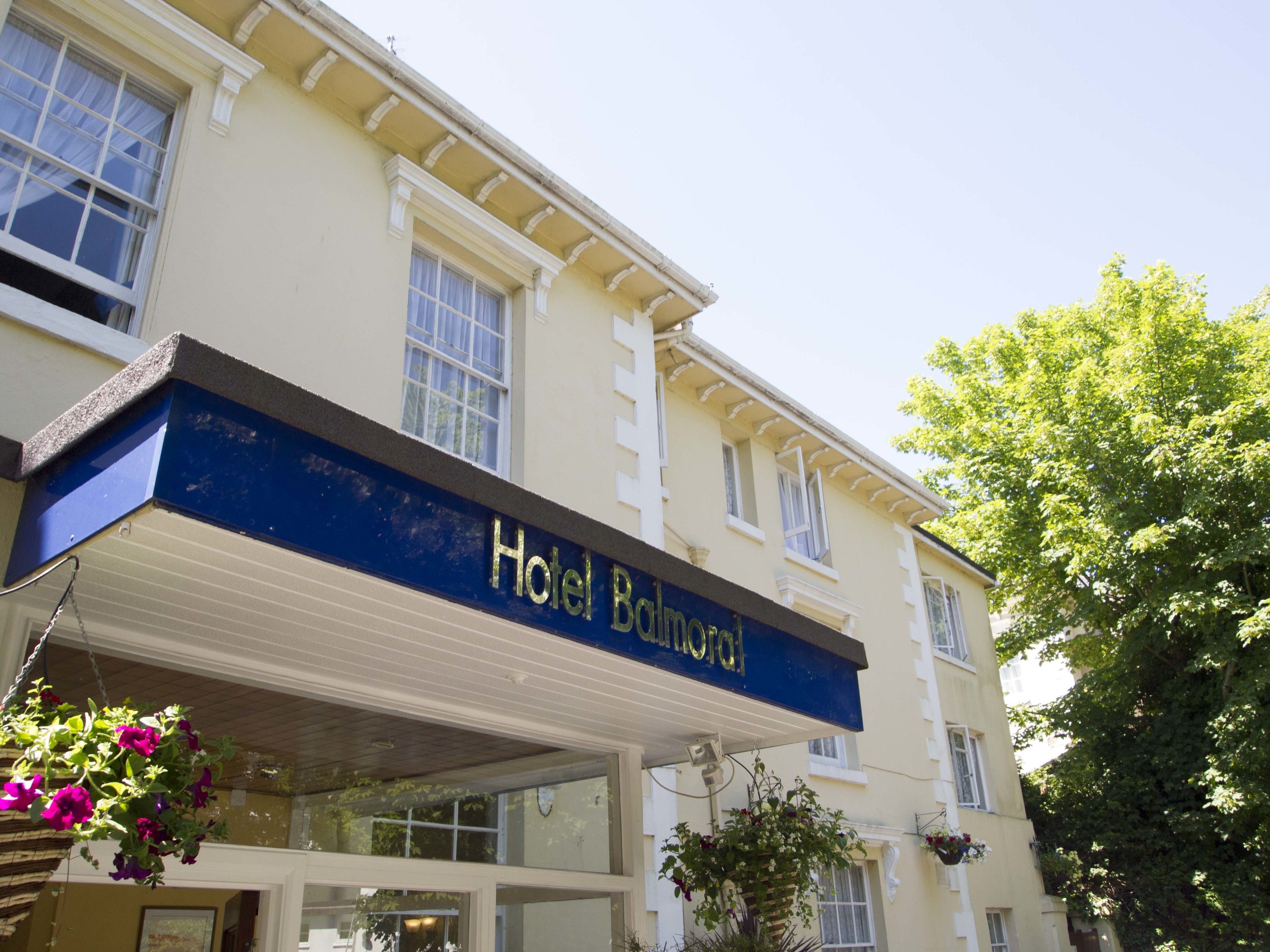 A hotel with a blue awning and a sign that reads "Hotel Balmoral."