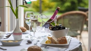 A table set for a meal with a bowl of mussels, bread, and a bottle of wine. - The Hotel Balmoral - Adults Only (Torquay)