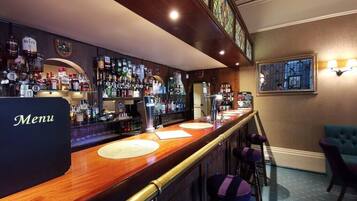 A bar area with a wooden counter, stools, and a menu sign.