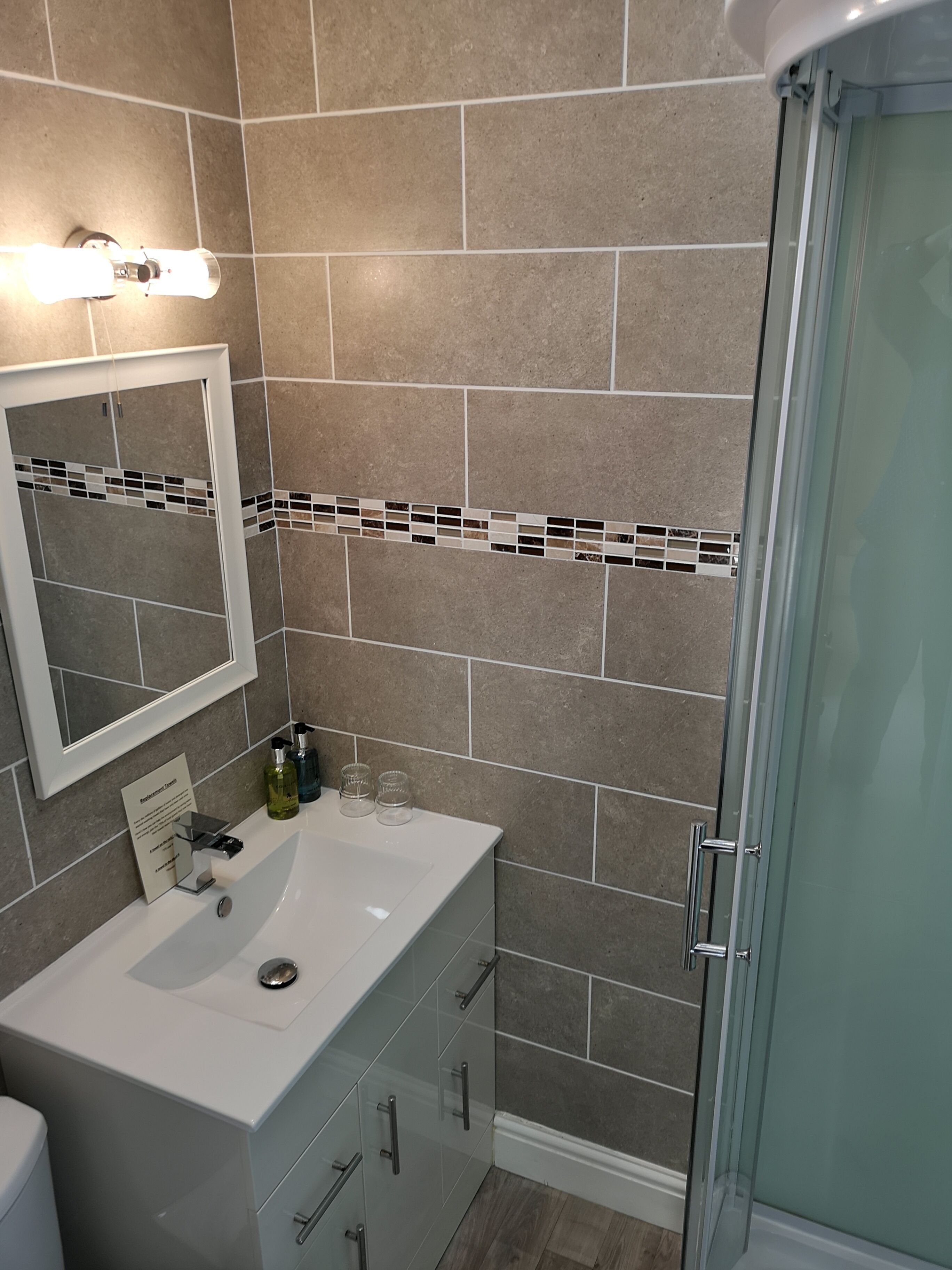 Une salle de bain avec un lavabo blanc, un miroir et un espace douche.