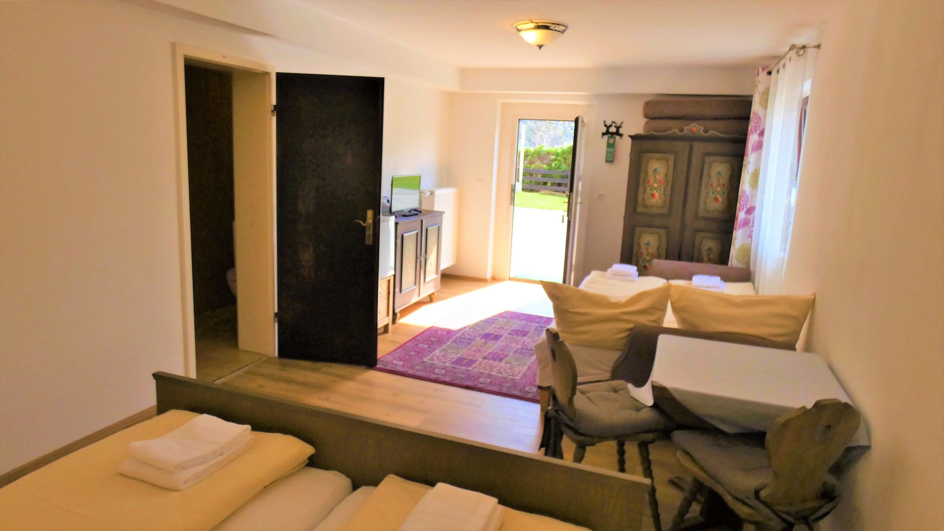 A hotel room with a bed, a chair, a desk, and a view of the outside.