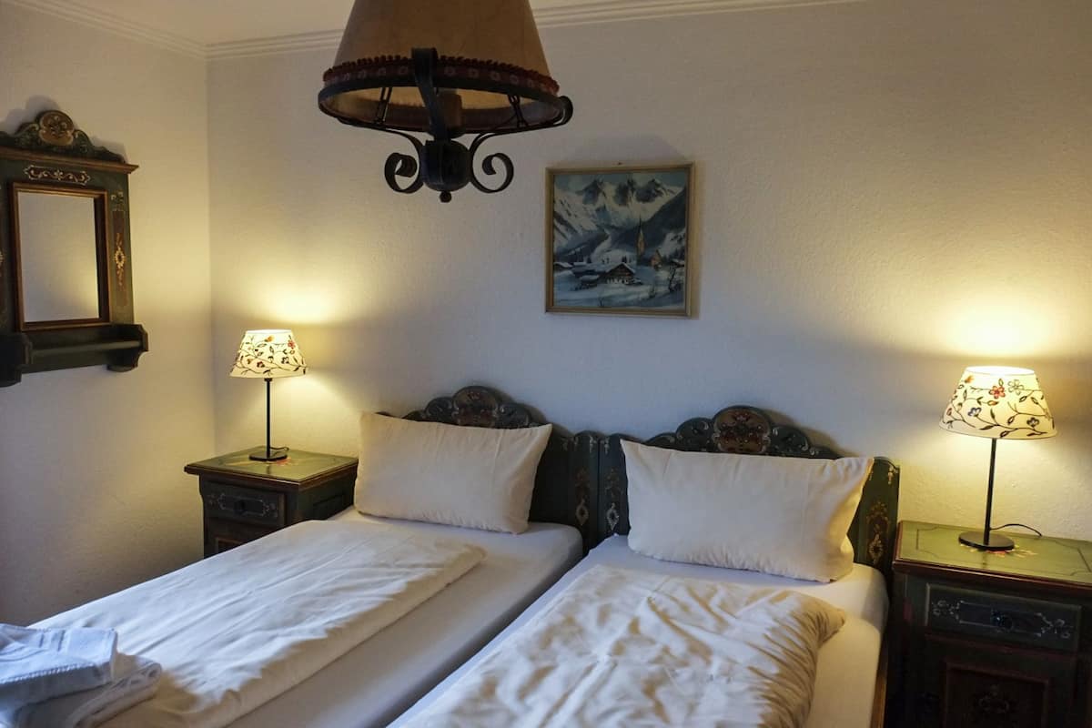 A double bed with two bedside tables, each with a lamp. A painting of a snowy landscape hangs on the wall.