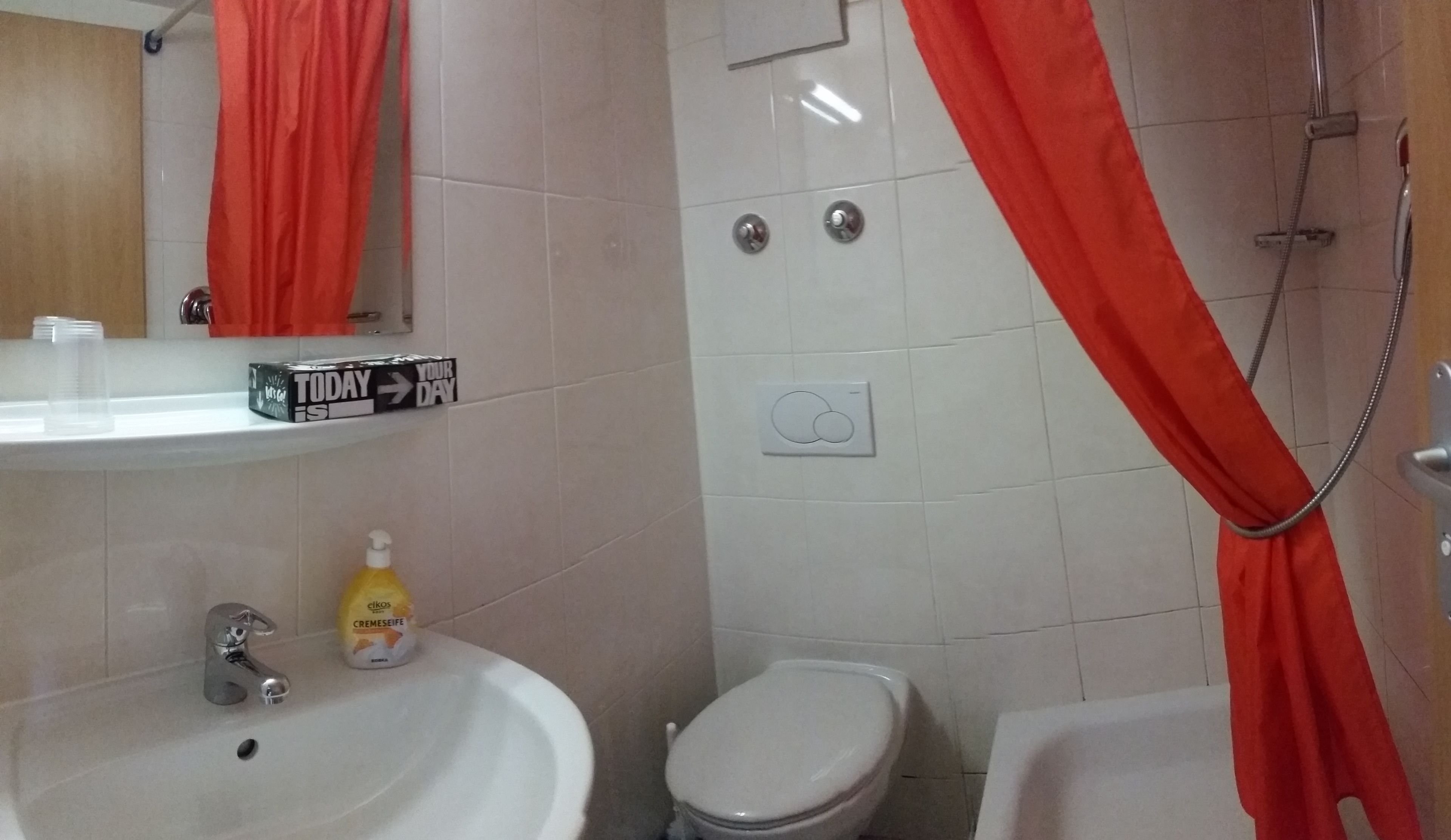 Un baño con lavamanos blanco, inodoro y zona de ducha.