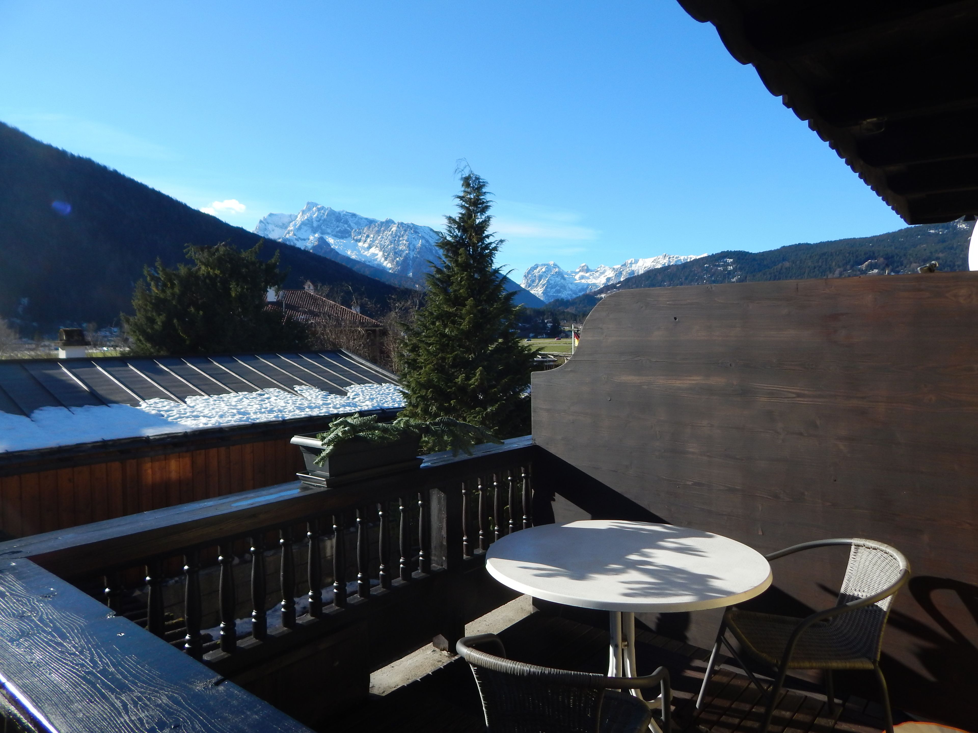 A balcony with a table and chairs, overlooking a snowy mountain landscape.
