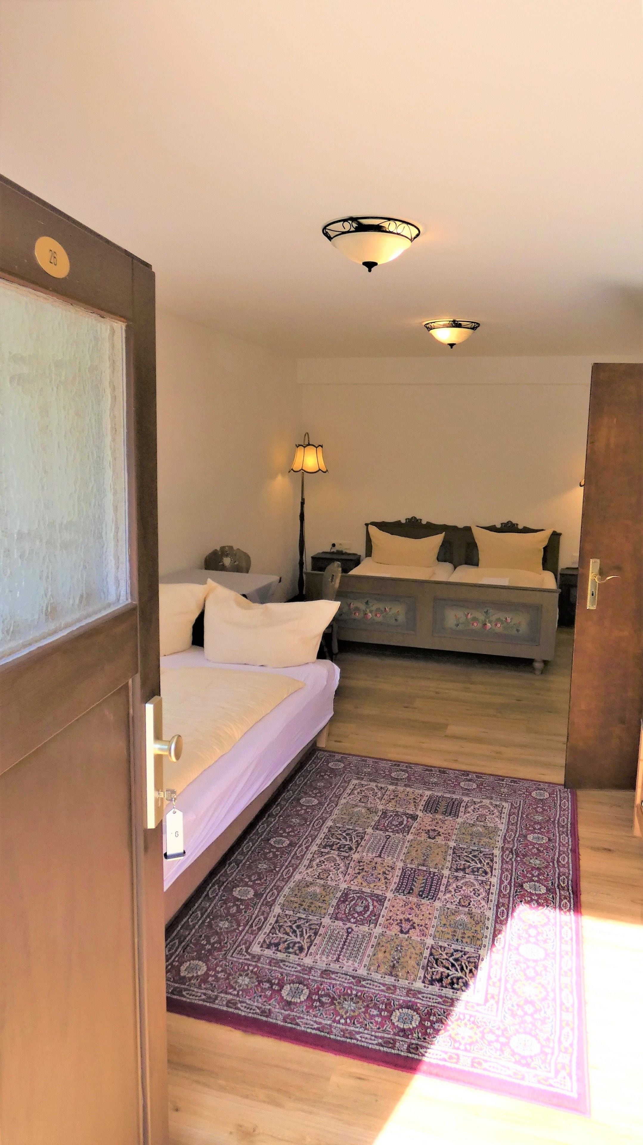 A room with a bed, a nightstand, a lamp, and a patterned rug.
