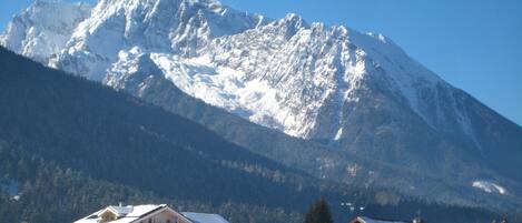 A hotel with multiple floors, balconies, and a snow-covered mountain in the background.