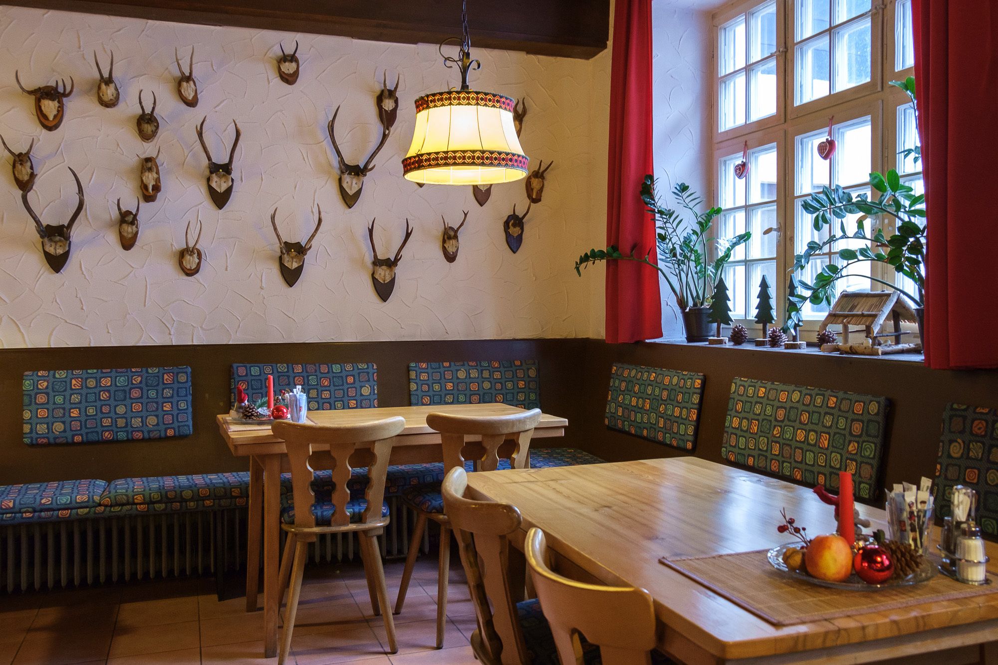 A restaurant interior with a long wooden table, multiple booths, and a wall adorned with mounted animal heads.