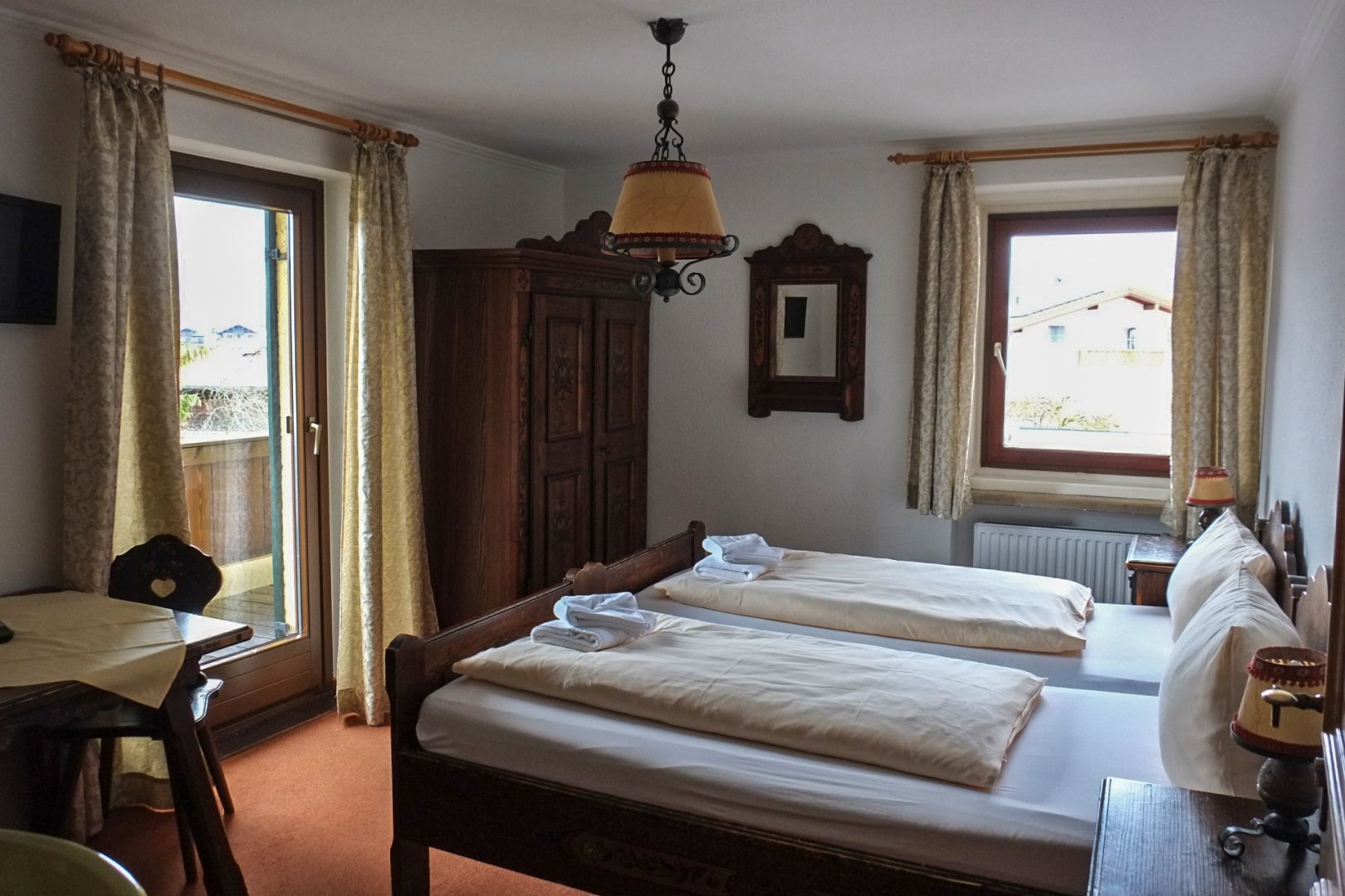 A room with two beds, a wooden wardrobe, a desk, and a chair.