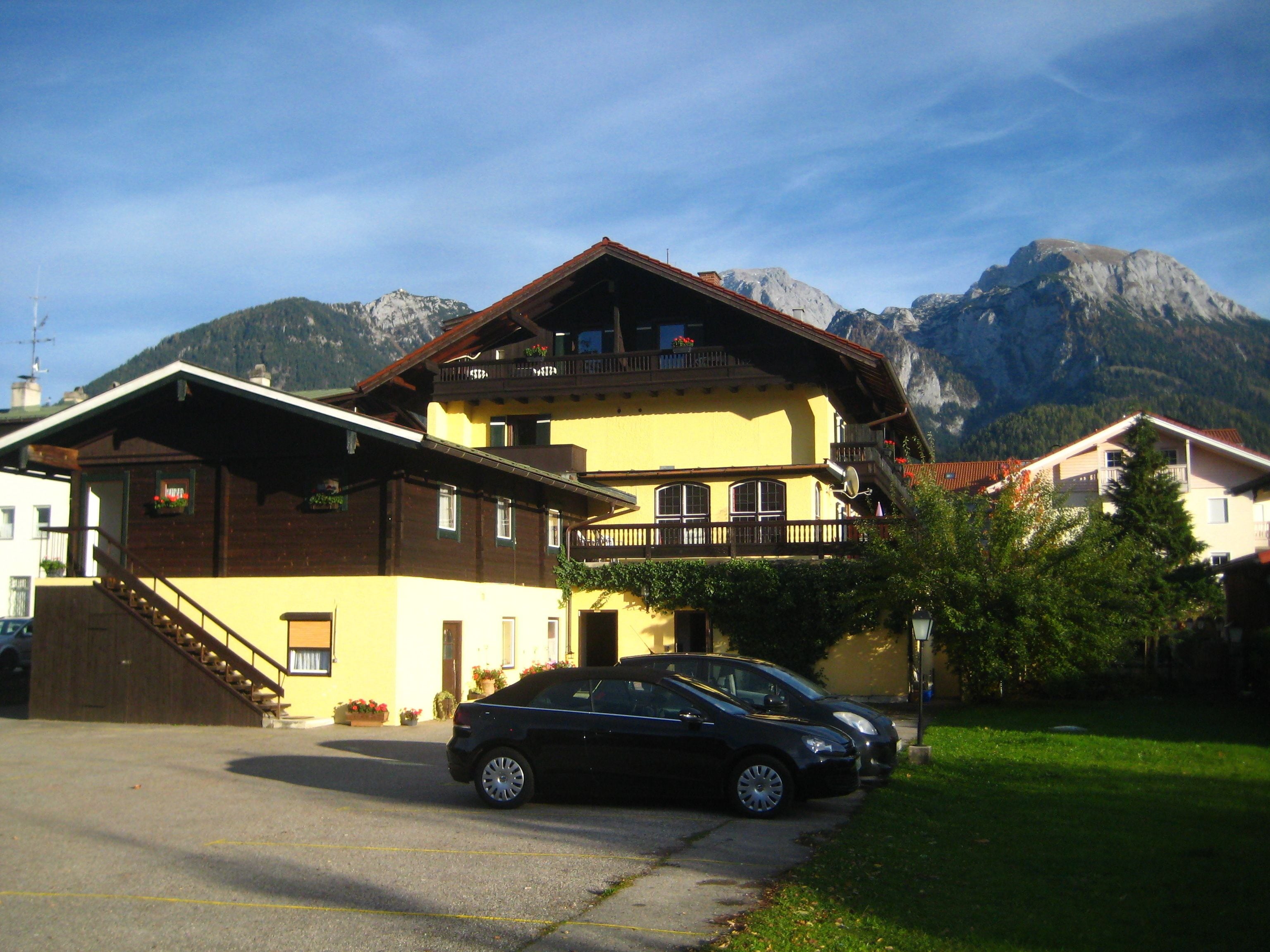 A two-story building with a balcony, a staircase, and a car parked in front.