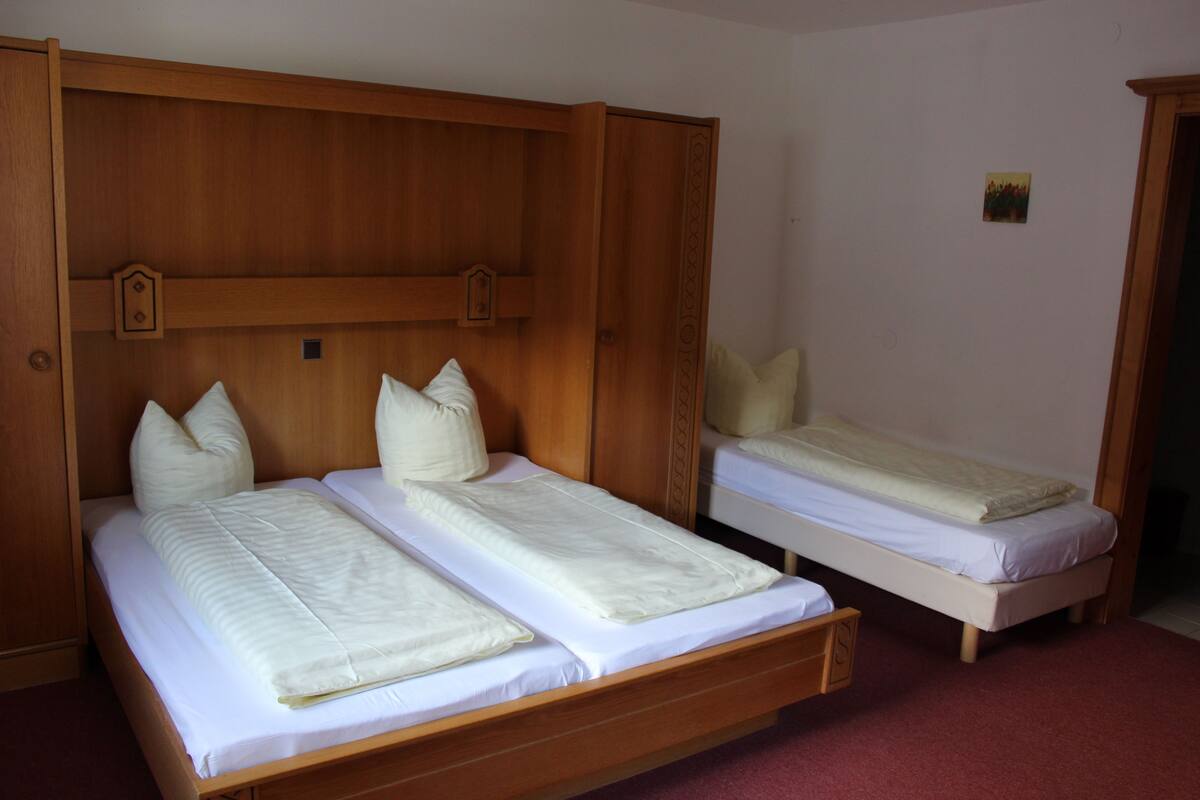 A room with two single beds, wooden headboards, and a small painting on the wall.