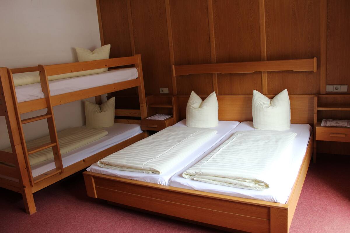 A room with two bunk beds, a wooden headboard, and a bedside table with a lamp.
