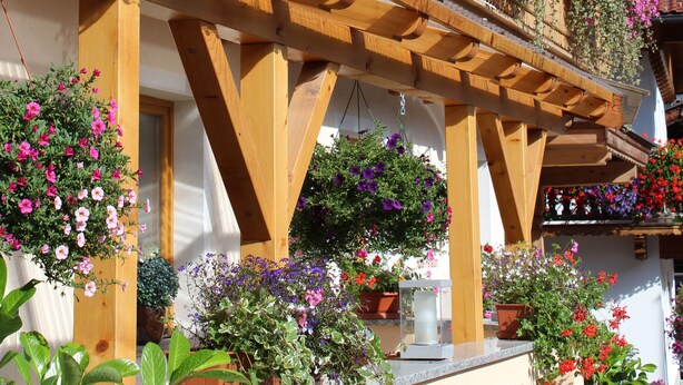A wooden building with balconies adorned with flowers. - Hotel Pension Almrose (Wildschönau)
