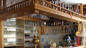 A bar area with wooden shelves, glassware, and liquor bottles. - Hotel Pension Almrose (Wildschönau)