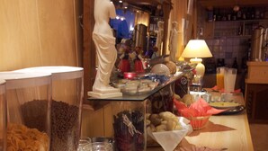 A buffet area with various food items, a statue, and a bar in the background. - Hotel Pension Almrose (Wildschönau)