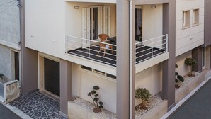 A modern two-story residential building with a balcony, stone pathway, and small potted plants. - Casa Vacanza Talia CaseSicule- few meters from the beach (Pozzallo)