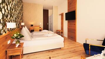 A hotel room with a bed, bedside tables, a TV, and a wooden wall.
