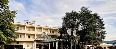 Un hotel con un atrio central de vidrio, un patio empedrado y zonas de estar al aire libre.