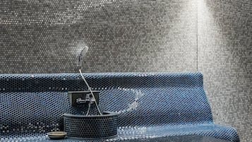 Un baño moderno con un banco azul con textura, un lavabo pequeño y una zona de ducha.