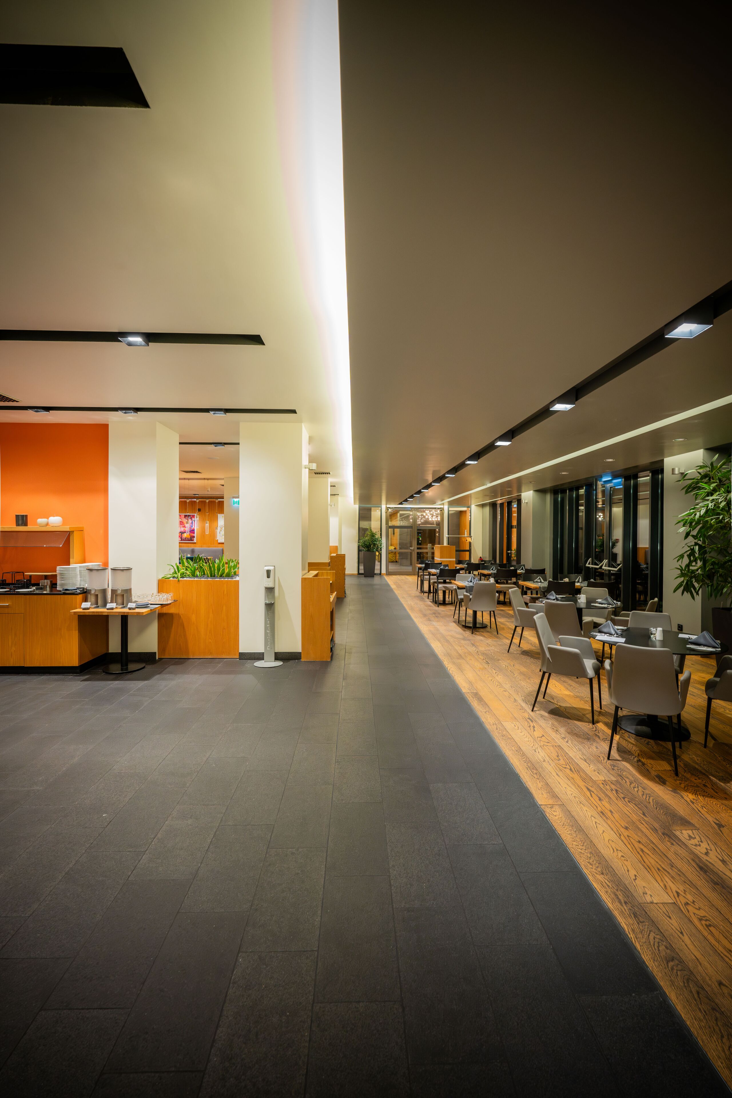 A modern hotel lobby with a reception desk, seating area, and a long corridor.