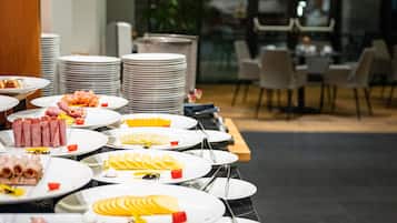 A buffet setup with various food items and stacked plates.