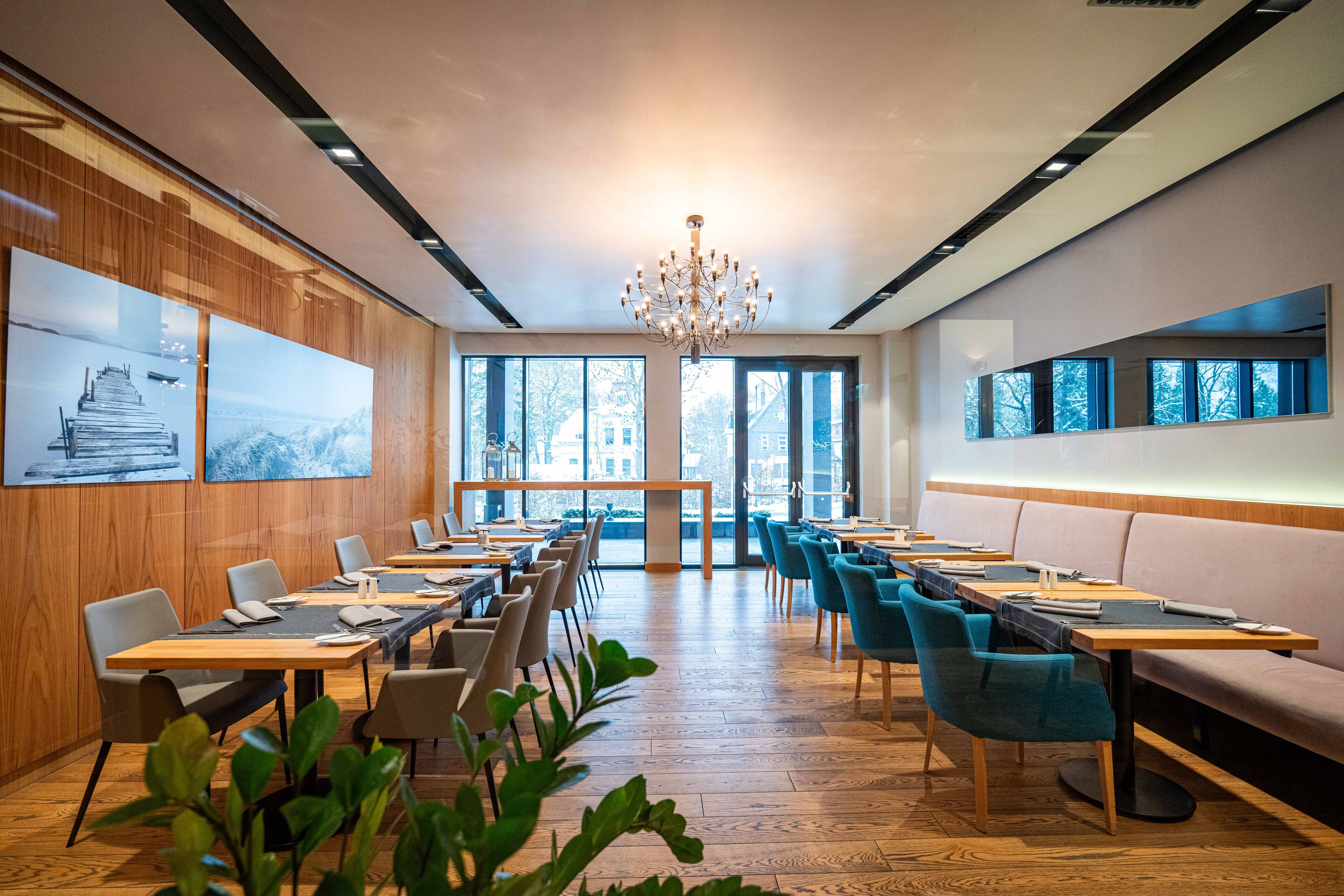 A modern dining area with wooden tables, blue chairs, and a chandelier.