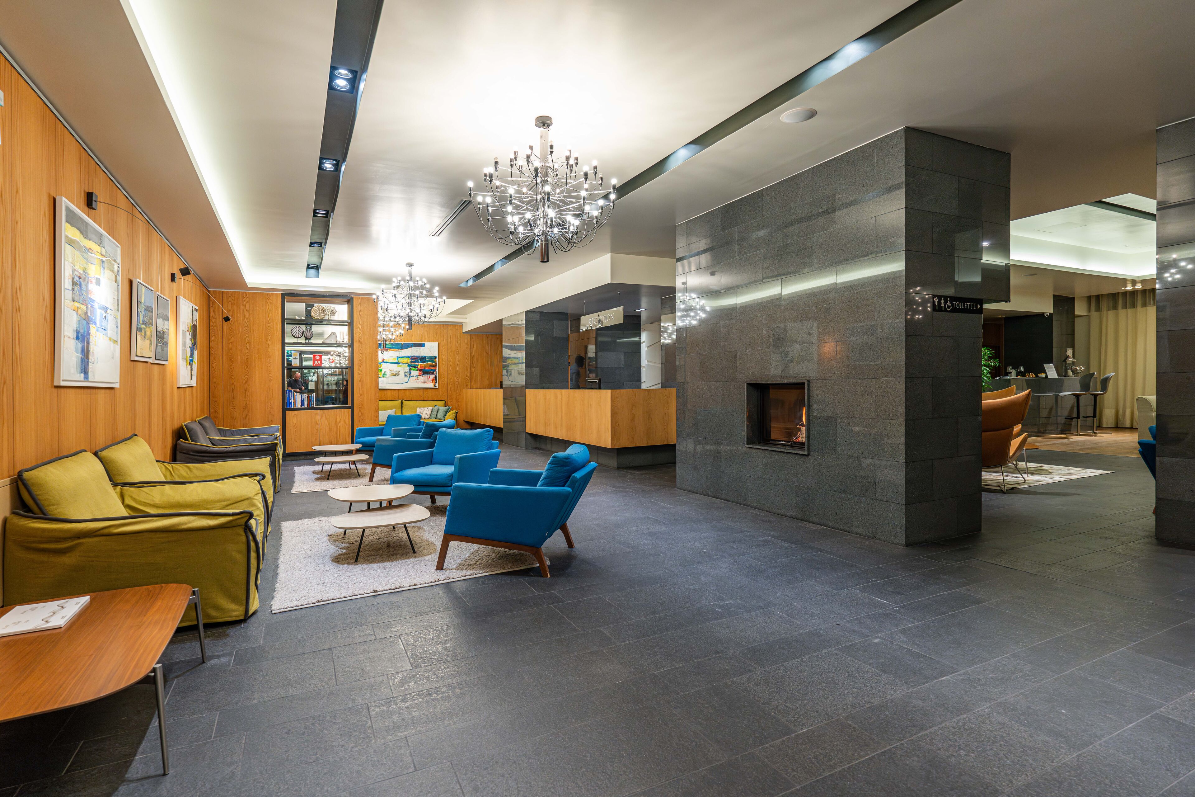 Een moderne lobby met een open haard, zithoeken en een receptiebalie.