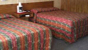 Habitación de hotel con dos camas, cabecero de madera, un cuadro en la pared y una mesita de noche con lámpara y teléfono.