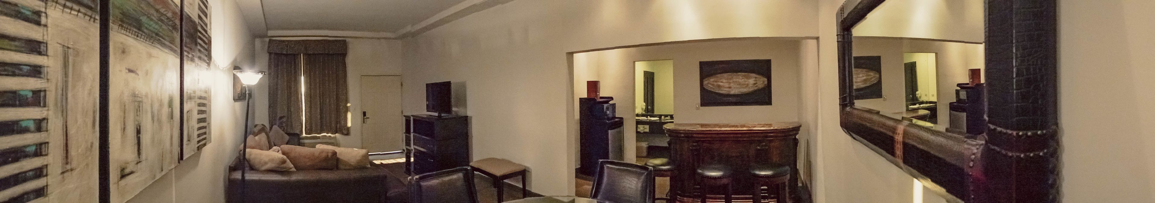 Un couloir comprenant un canapé, des fauteuils, une table et un coin bar.