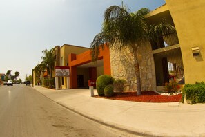 A hotel with a stone facade, palm trees, and a red sign indicating a conference center.