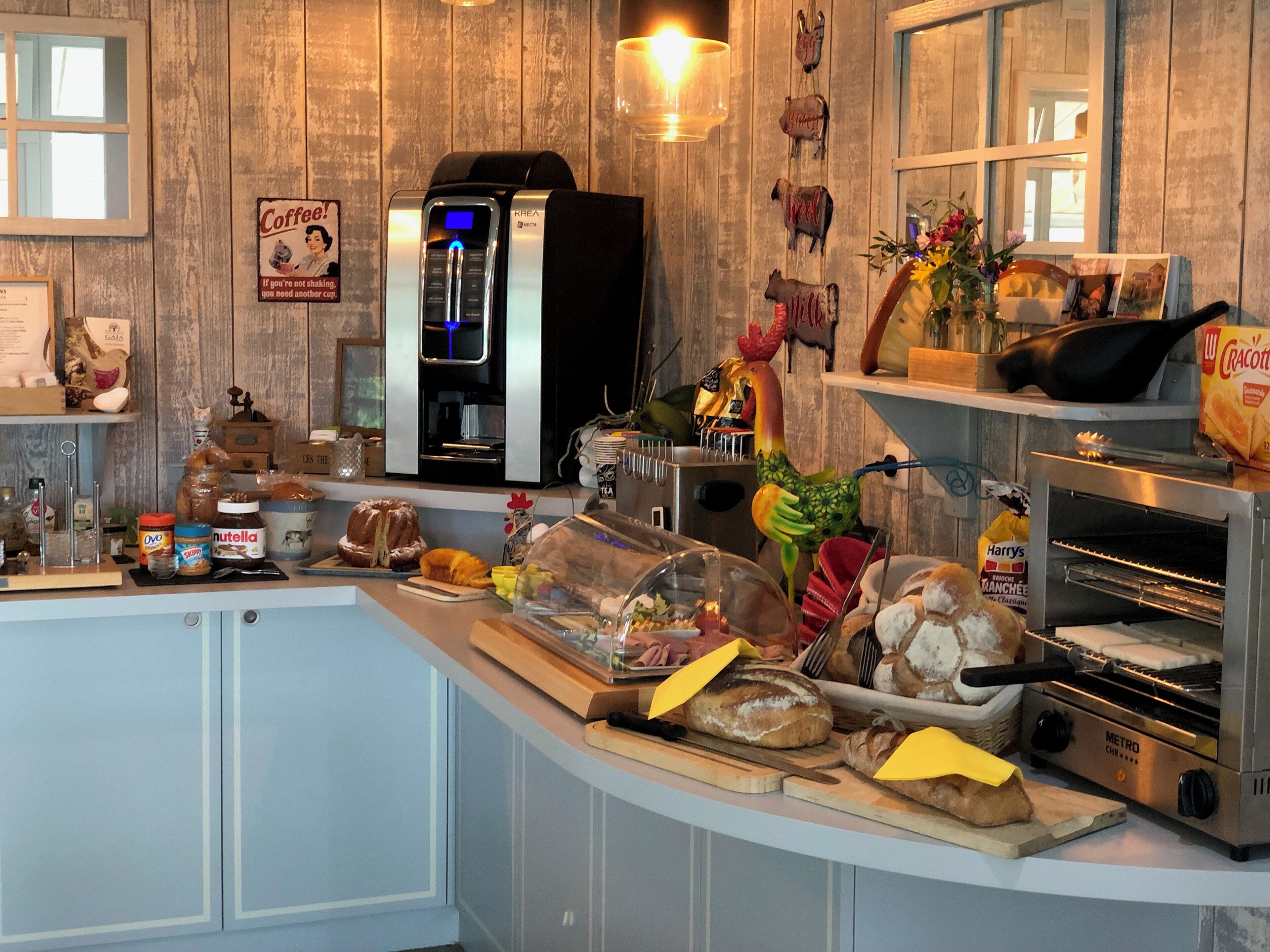A kitchen with a coffee machine, toaster, and a variety of breads and pastries.