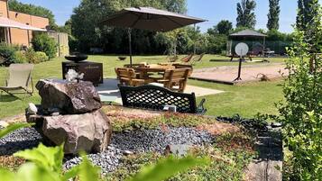 Un patio con una mesa y sillas, una chimenea y una formación rocosa.