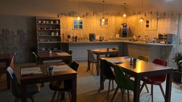 Una cocina moderna con una isla central, estanterías integradas y un comedor con múltiples sillas.