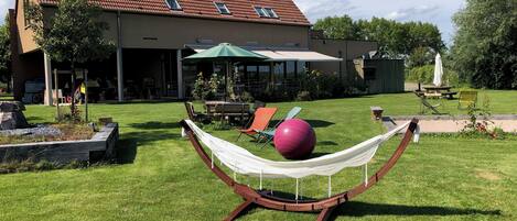 A house with a red-tiled roof, a hammock, a large exercise ball, and outdoor furniture.