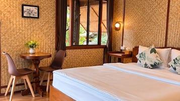 Un dormitorio con una cama grande, un escritorio con una silla, un ventanal con cortinas y un aire acondicionado instalado en la pared.
