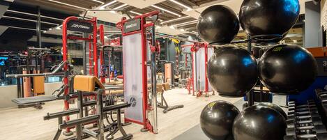 A gym with exercise equipment, including a squat rack, dumbbells, and medicine balls.