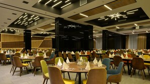 Un comedor amplio con varias mesas y sillas, dispuesto en un ambiente moderno con suelo de madera e iluminación contemporánea.