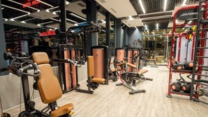 Un gimnasio moderno con diversas máquinas de ejercicio, estantes para pesas y suelo de madera.