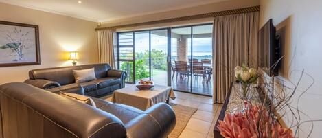 A modern living room with a leather sofa, a small table, and a TV mounted on the wall.