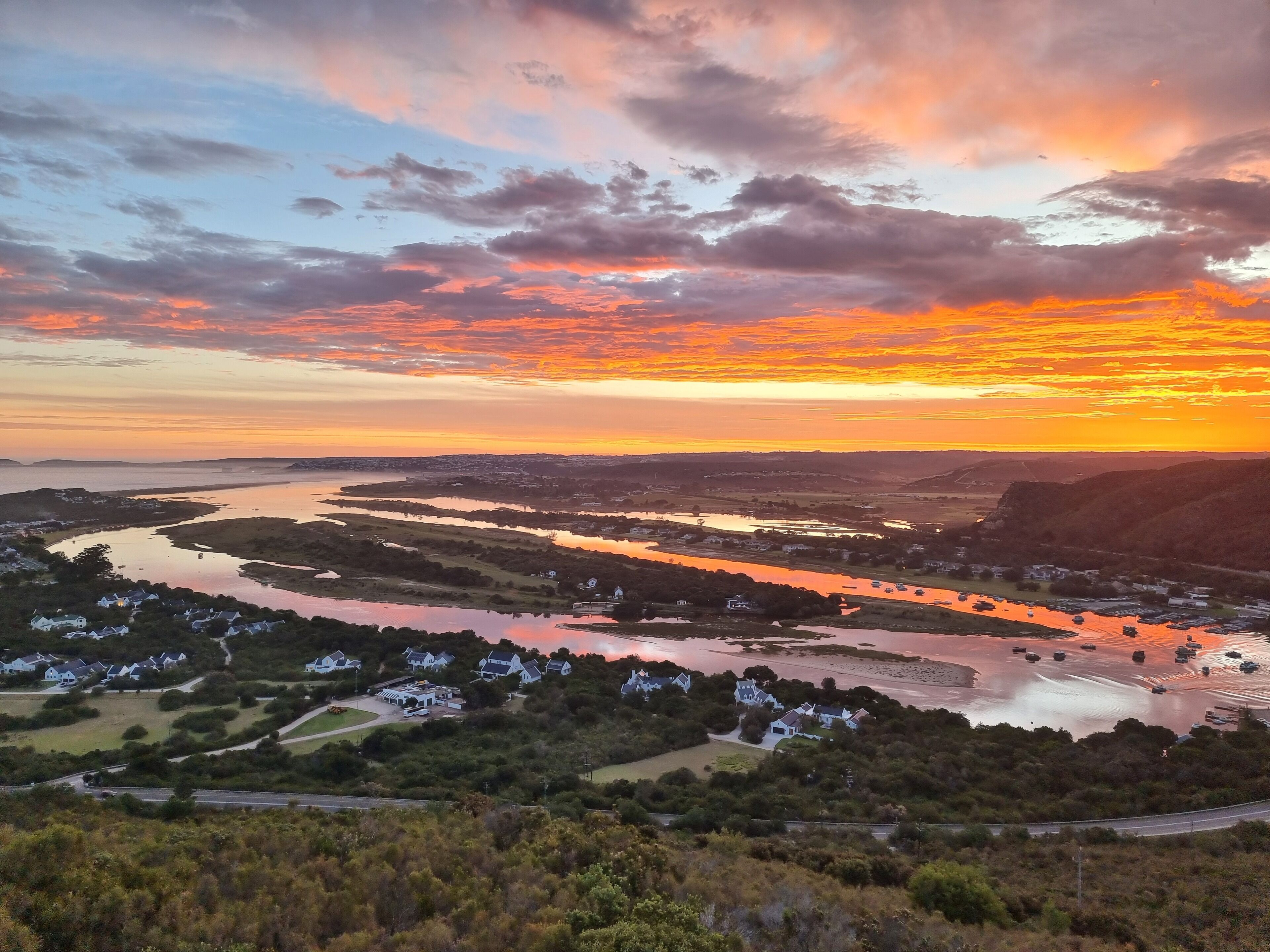 Eine malerische Flusslandschaft mit Häusern am Ufer, umgeben von Hügeln.