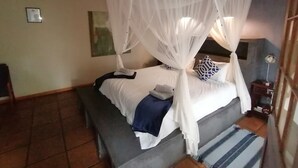 Un llit amb dosser, una taula de nit amb una làmpada i un quadre penjat a la paret.