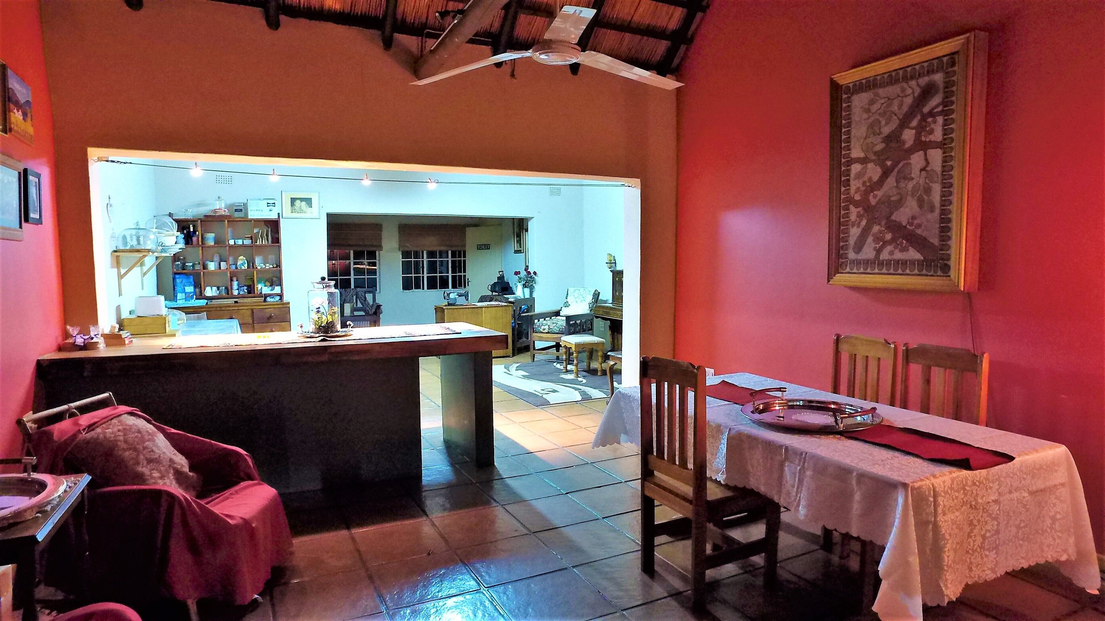 Un coin repas avec une table dressée pour deux personnes, une chaise et une petite table sur laquelle est posé un objet décoratif.