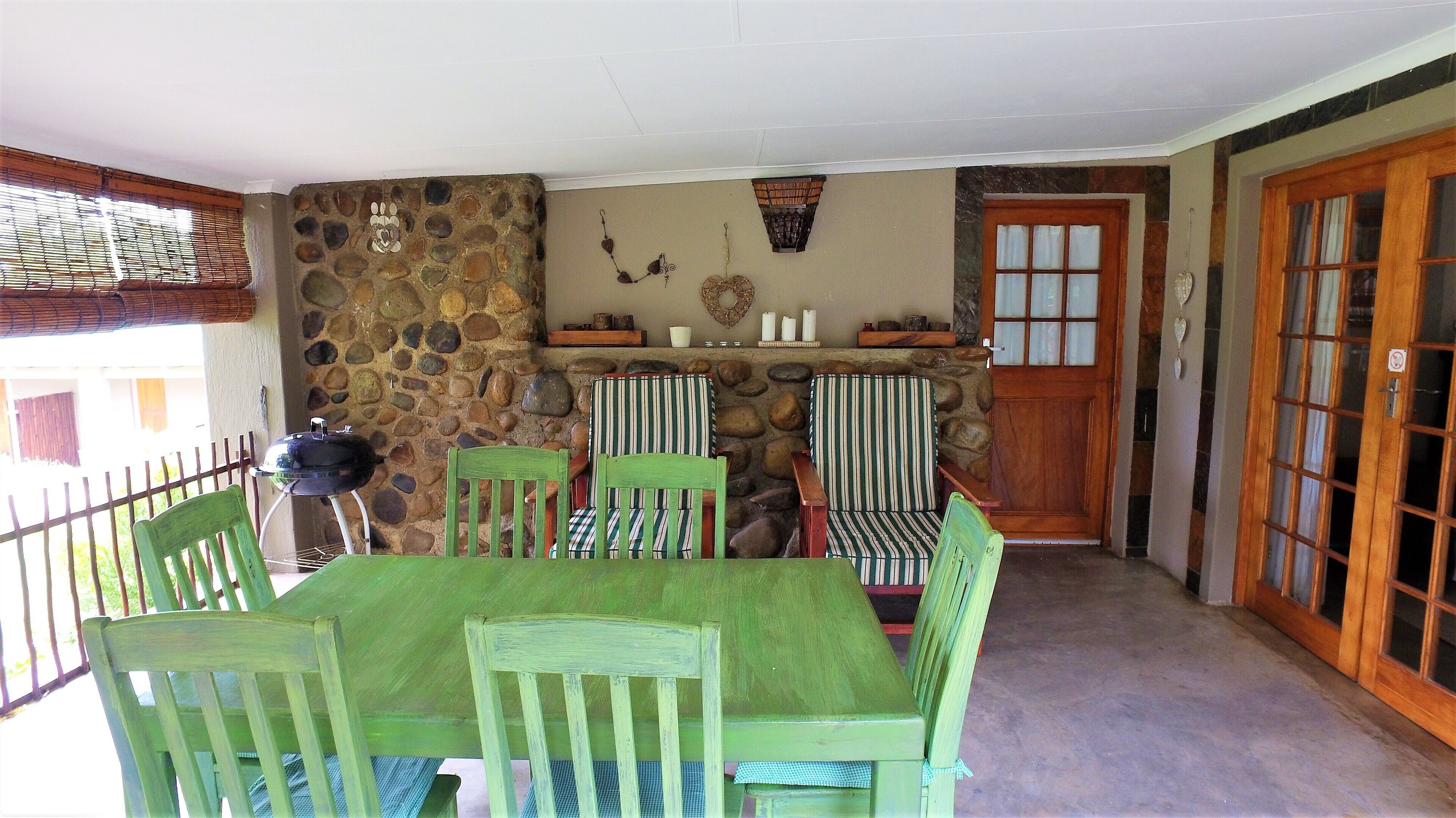 A patio area with a stone wall, a wooden door, and a table with chairs.