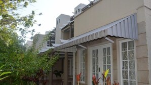 Um edifício residencial com um espaço de varanda coberto, janelas emolduradas por branco e fachada bege.