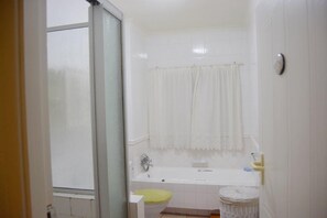 Une salle de bain avec une baignoire, des toilettes et un panier en osier.